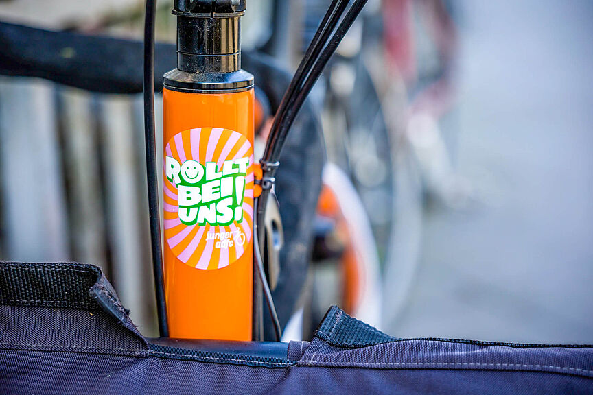Junger ADFC Ein orangefarbener Fahrradrahmen mit einem bunten Aufkleber.